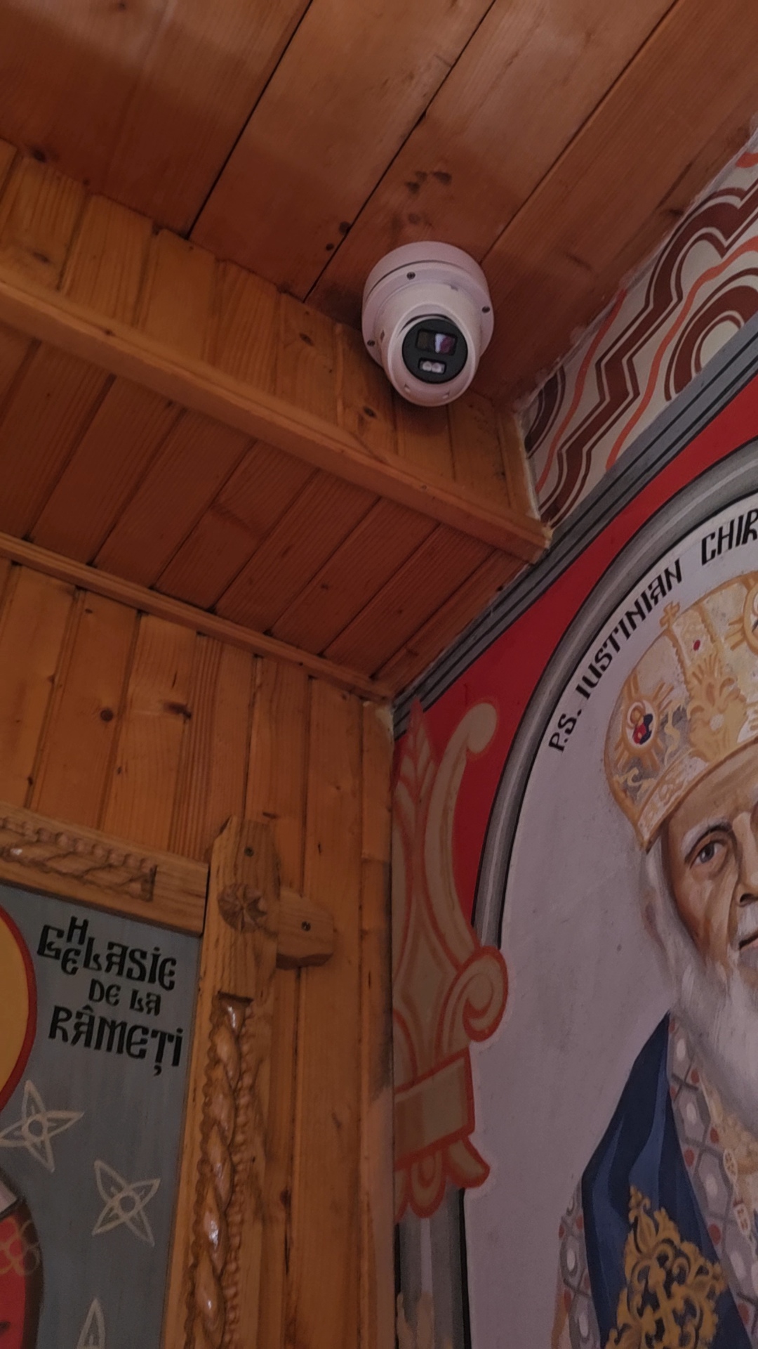 Cameră dome de supraveghere montată discret pe tavanul de lemn al unei biserici pictate