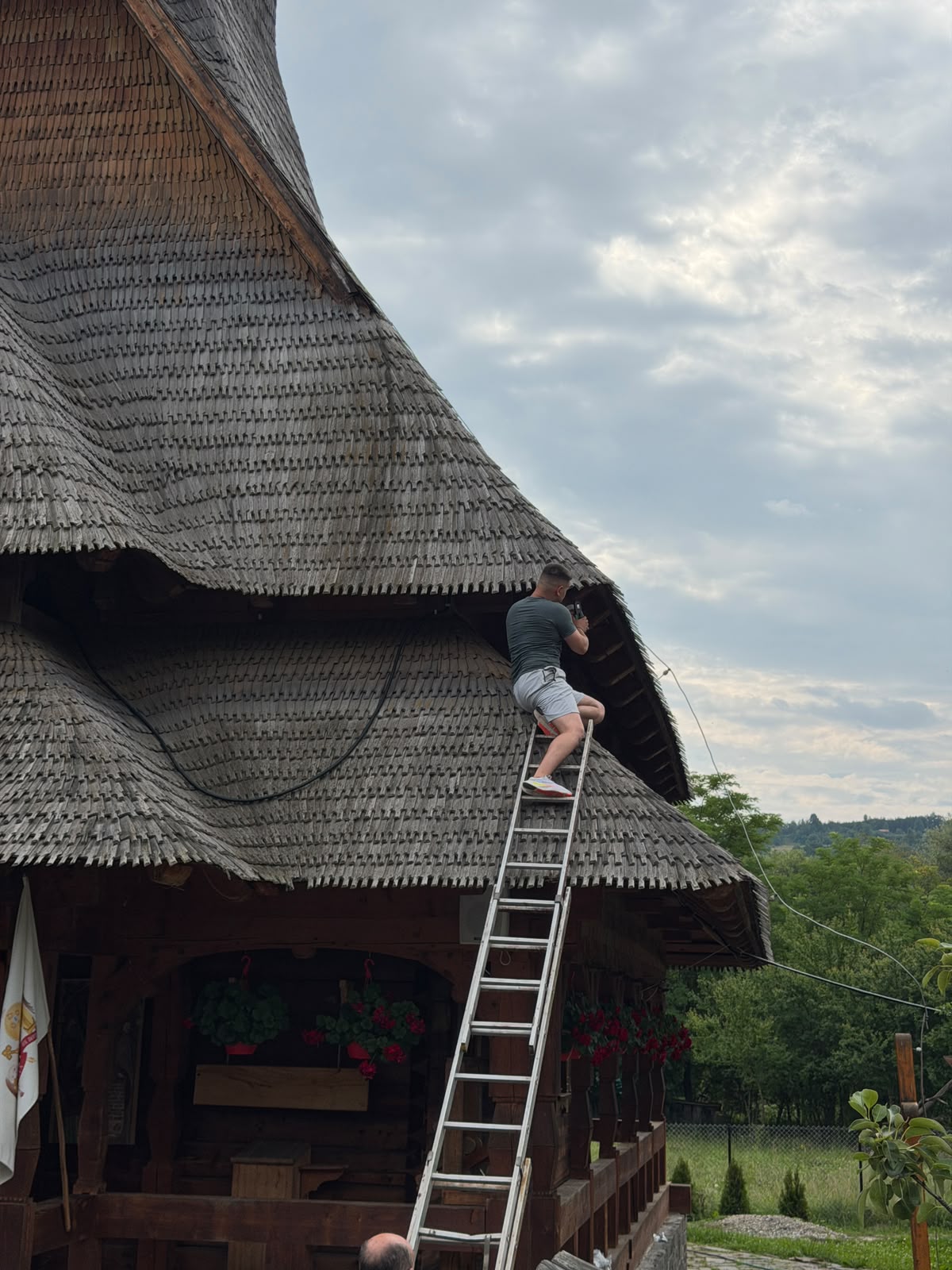 Tehnician BUNGARZAN ENTERPRISE instalând camere de supraveghere pe acoperișul unei biserici de lemn