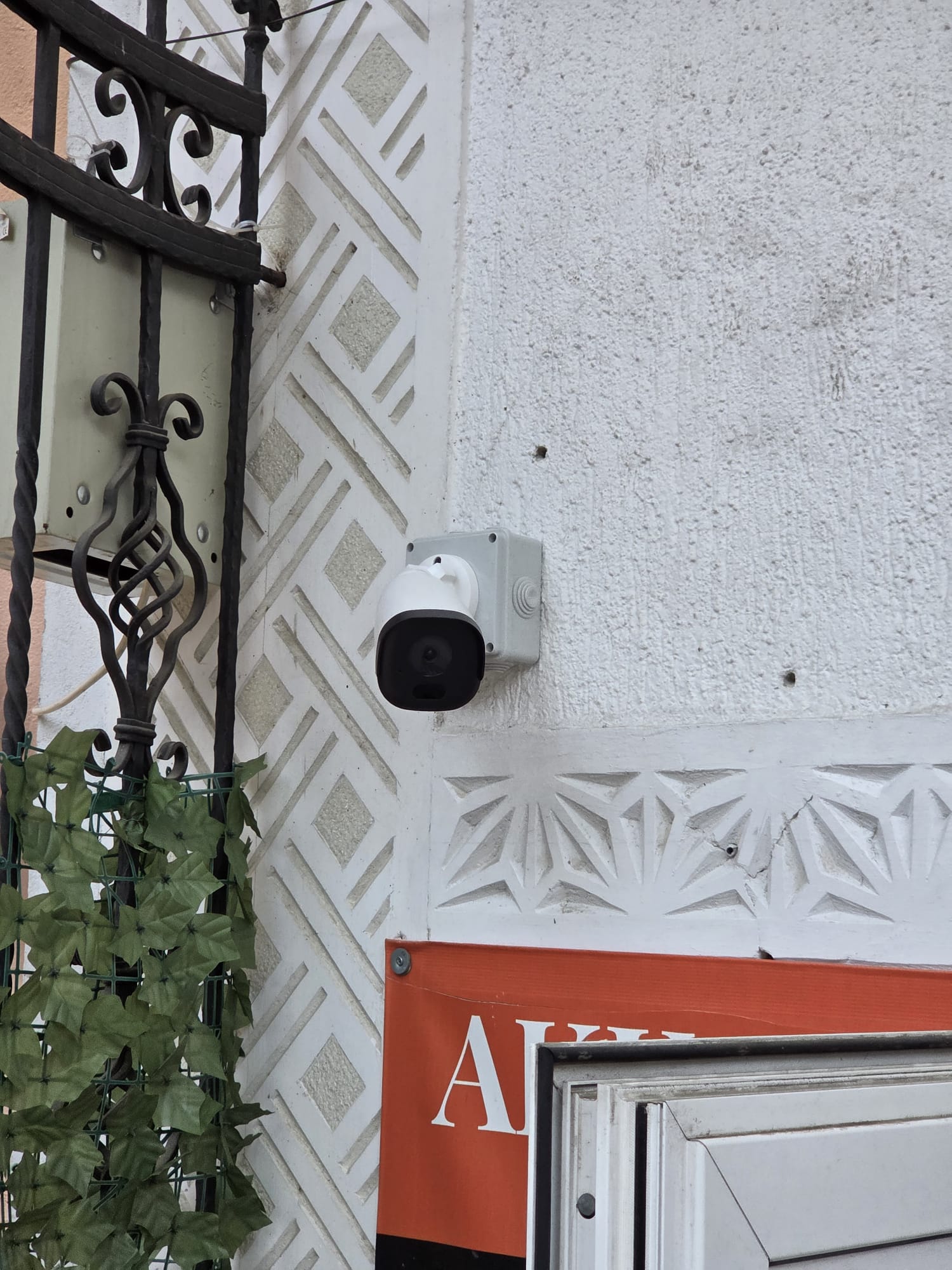 Cameră de supraveghere cu doză etanșă montată la intrarea unui magazin pentru monitorizarea accesului